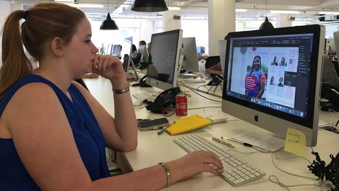 Amy looking at a layout from guiding magazine on a mac computer