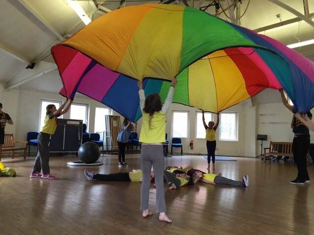 Brownies playing a game with a parachute for International Women's Day