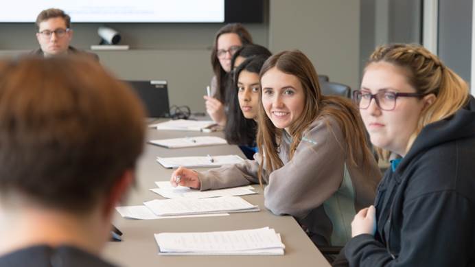 Group of young women from The Senior Section talk around a board room table