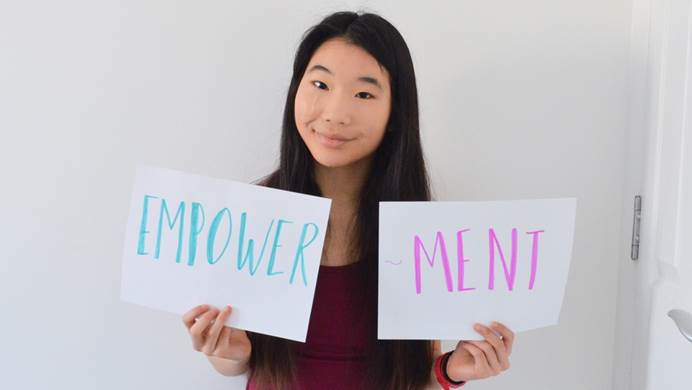 Young woman holding hand written sign that says empowerment