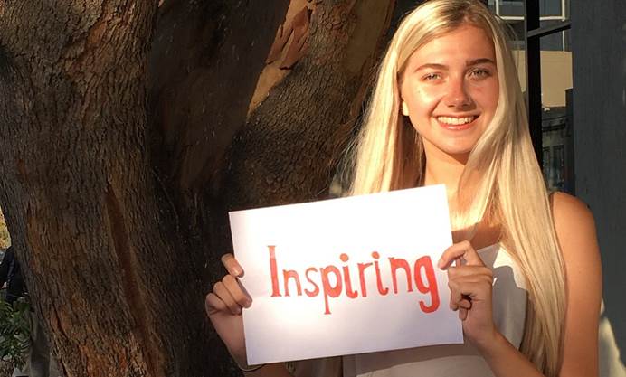 Young woman holding hand written sign that says inspiring