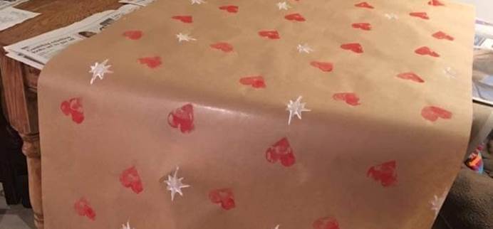 A present covered in home made wrapping paper, made from brown parcel paper decorated with heart-shaped stamps.