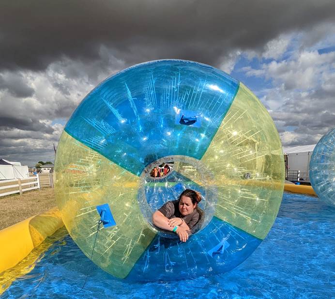 Fran is in a blue and yellow zorb, which is on water in a pool