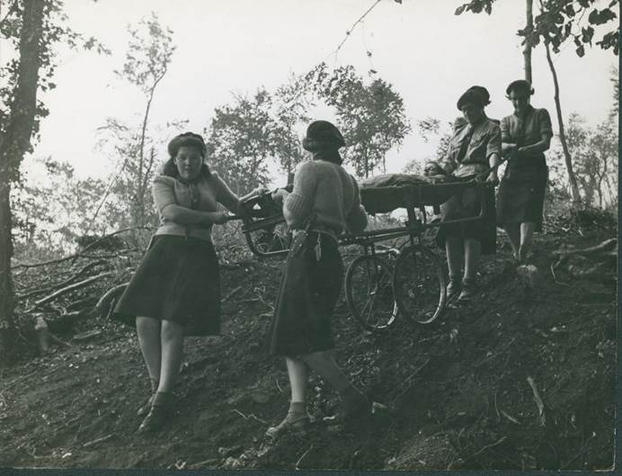GIS volunteers in training in 1943. They have the upper parts of a cart placed end to end to make a wheeled stretcher.