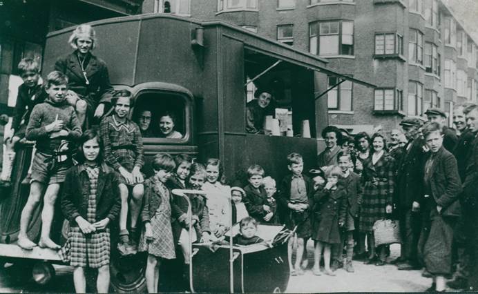 GIS members distributing food out of a van to children in Holland, 1945.