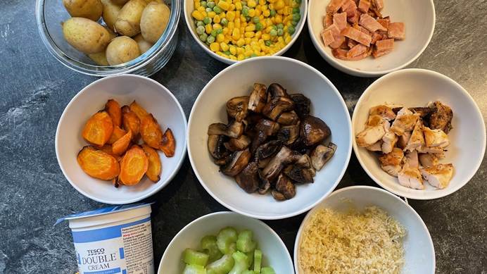 8 bowls filled with ingredients of potatoes, sweetcorn and peas, chopped ham, carrots, mushrooms, celery, cheesy, a stock cube and a pot of cream.