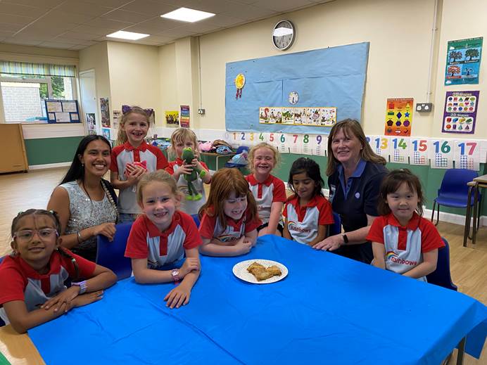 Rainbows sat around a table with their leaders eating samosas