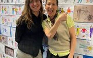 2 women standing in front of a wall of designs