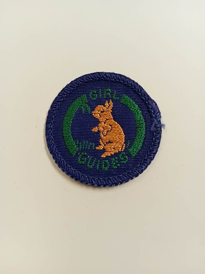 Round navy badge with a yellow embroided rabbit on the front.
