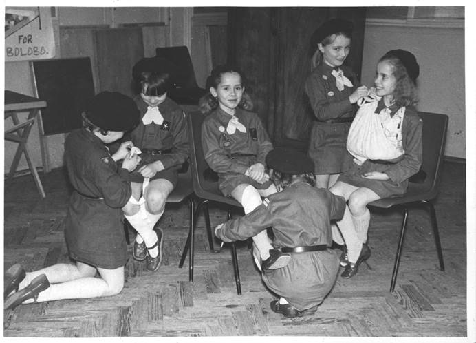 Black and white image of Brownies practising first aid, 1970