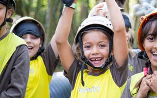 A group of Brownies in uniform cheer. They're wearing hats and smiling