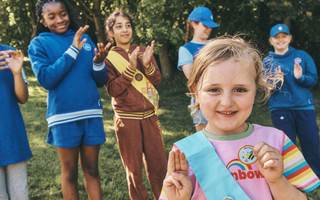Rainbow does promise sign surrounded by Brownie, Guide and volunteer