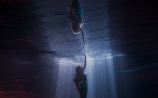 Underwater shot of mermaid Ariel reaching out towards the surface