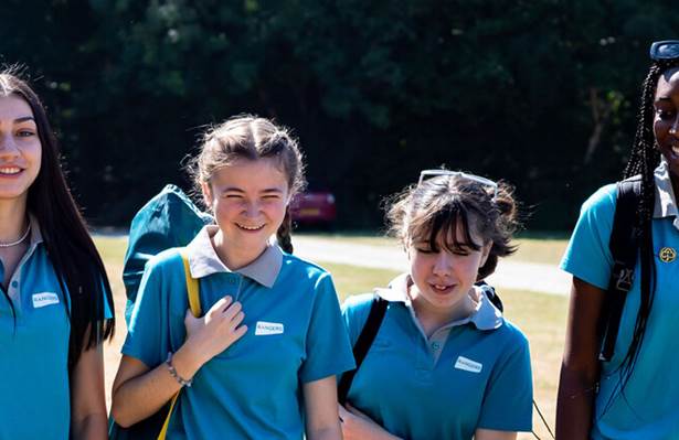 Group of girls in Ranger uniform walking outdoors and facing towards the camera, laughing