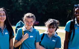 Group of girls in Ranger uniform walking outdoors and facing towards the camera, laughing