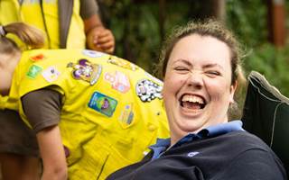 Laughing woman in navy Girlguiding volunteer uniform sitting on a camp chair