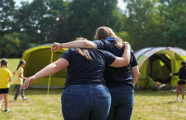 Volunteers embracing outdoors, facing away from camera