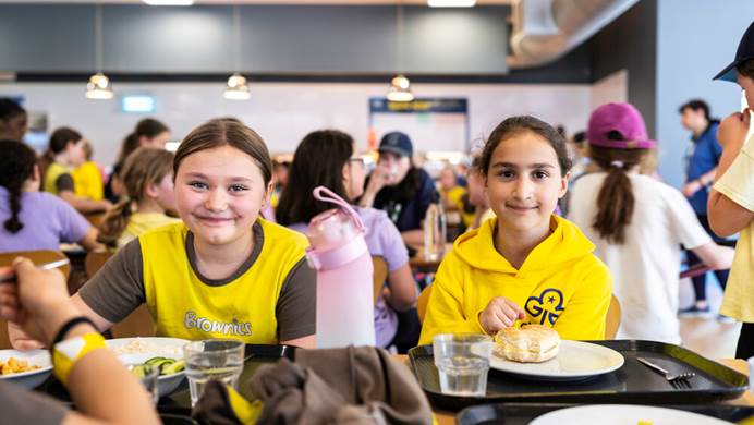 2 girls in Brownie uniorms sitting in a canteen